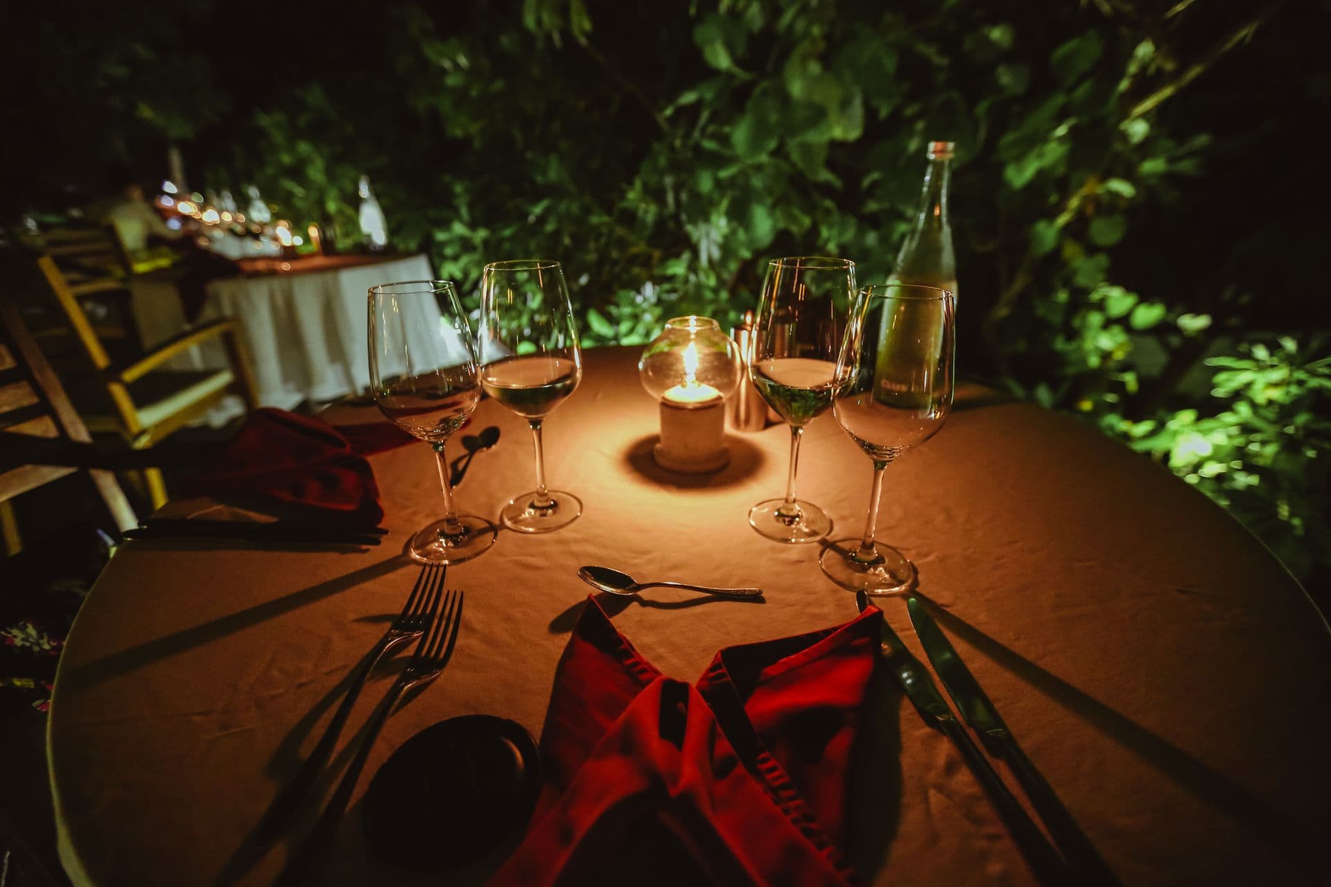 Mesa vestida con velas encendidas y copas, en tonos oscuros